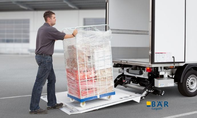 Mann schiebt Rollbehälter auf die Plattform einer BÄR Ladebordwand, die an einen Transporter montiert ist