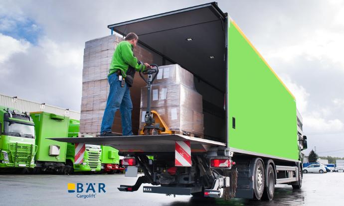 Lkw-Fahrer schiebt Paletten mit Hubwagen von der BÄR Lift-Plattform in den Lkw