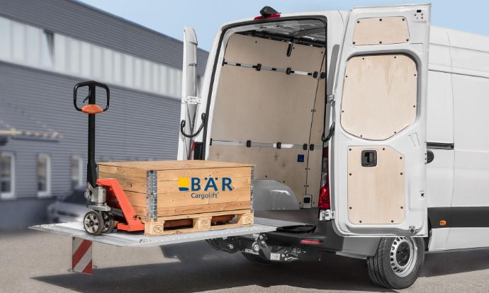 Auf der aufgefalteten, angehobenen Plattform des Bär VanLift steht eine Palette mit Hubwagen